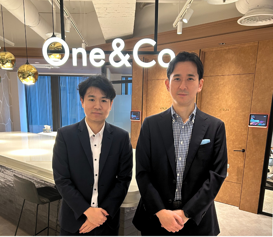 One&Coのサイン前で撮影された、今回のインタビューに登場したファルコンさんと渡邊さんの写真